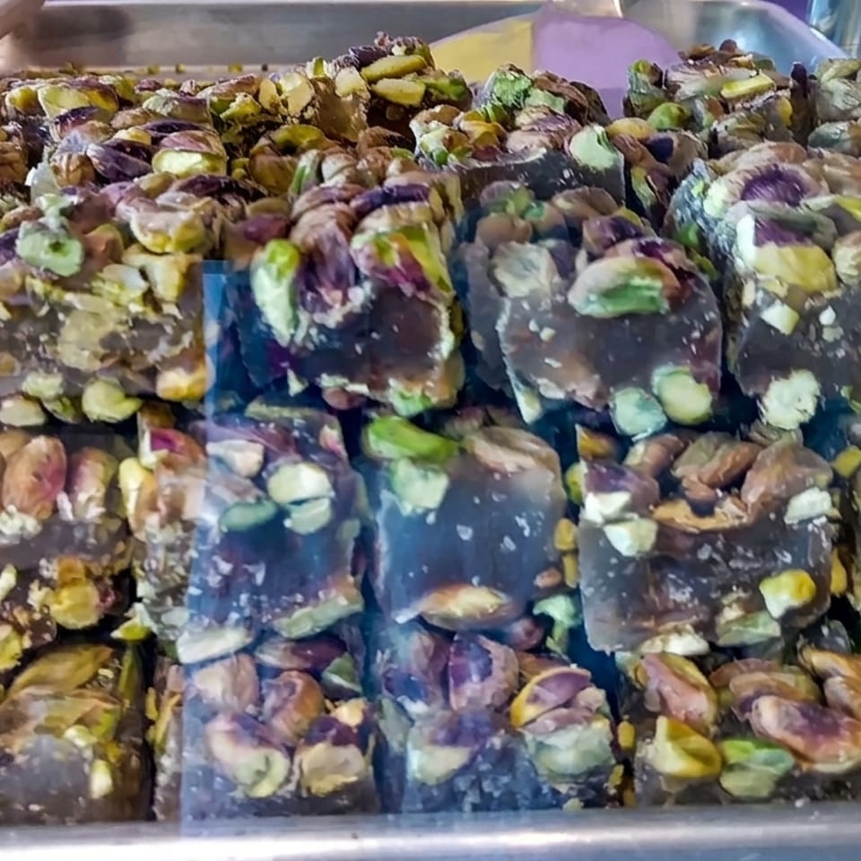 Rows of chocolate-coated pistachio and nut bars displayed in a metal serving tray.